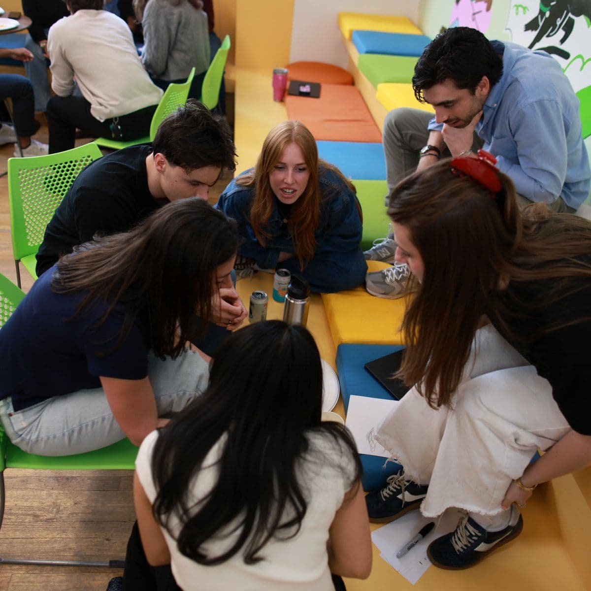 A small group huddles over notes on the colorful bleacher seating