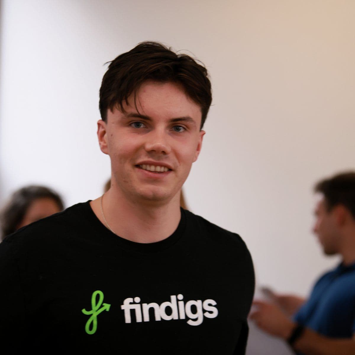 A teammate in a Findigs tee smiles at the camera in the office