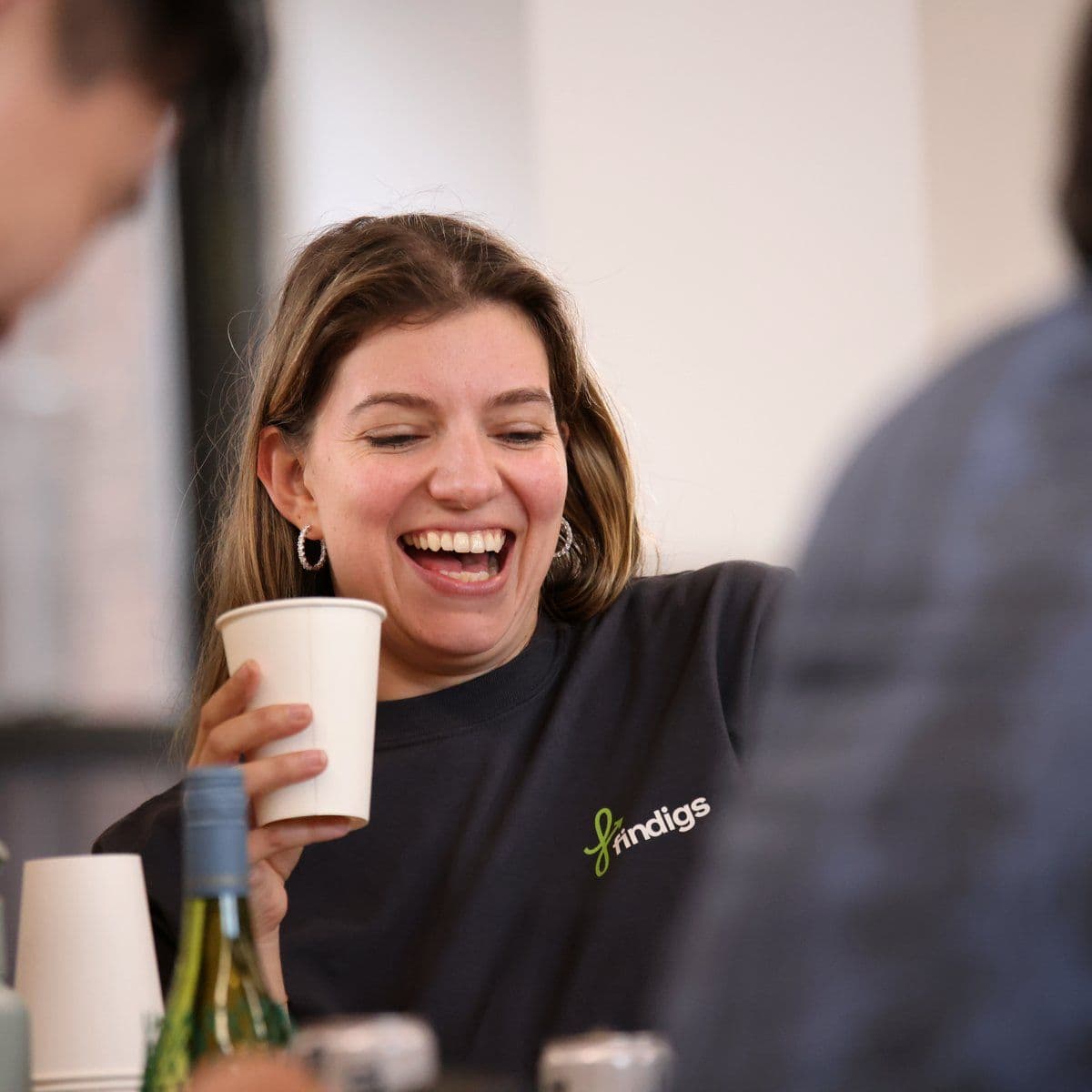 A teammate laughs over coffee at a team lunch